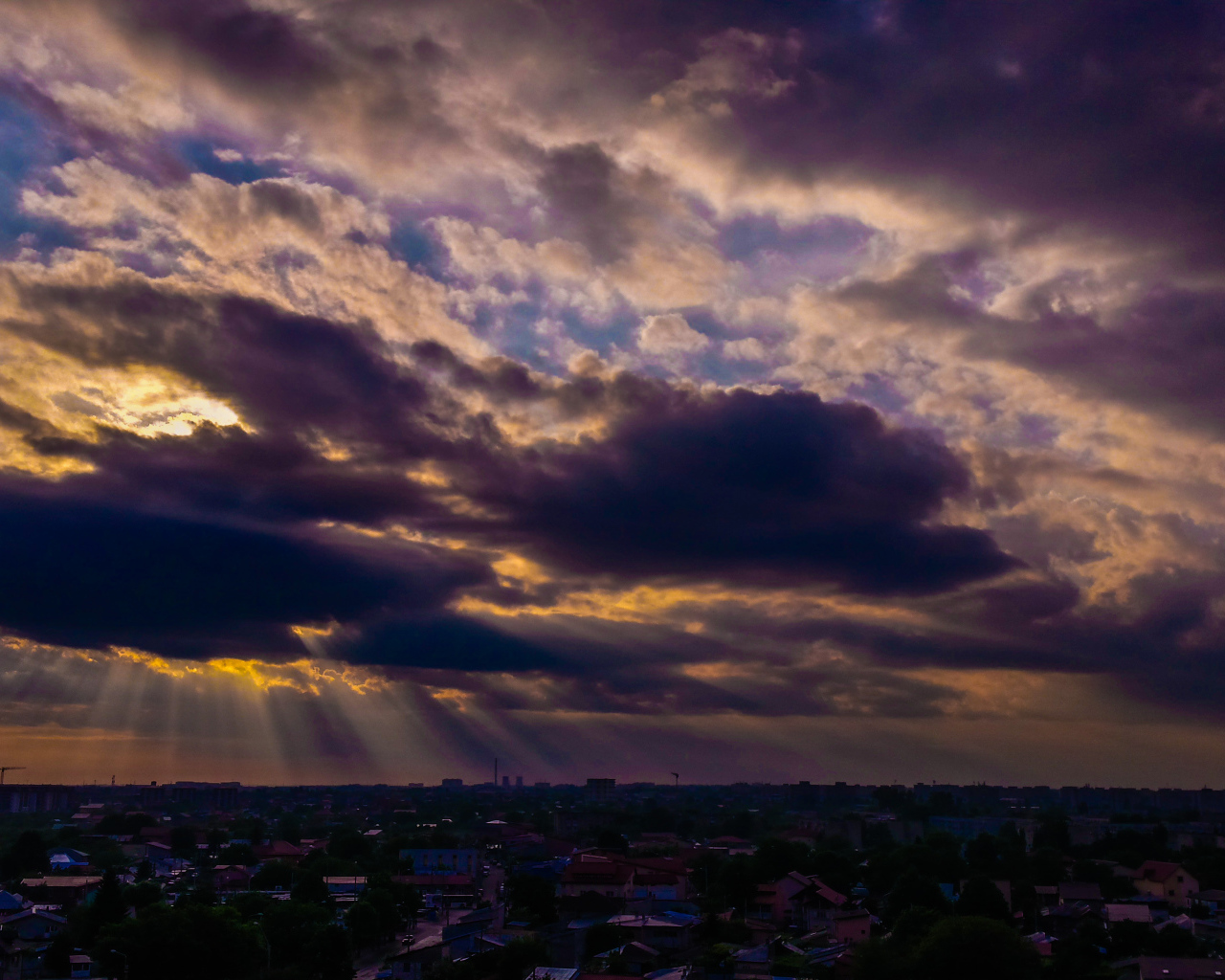 Лучи солнца пробиваются сквозь облака над городом