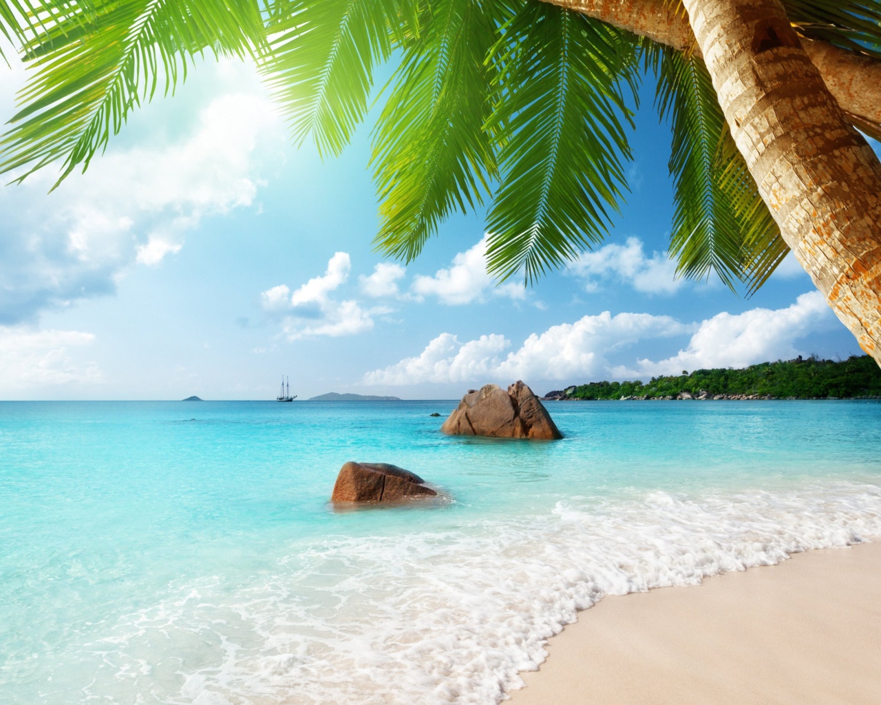 Голубая вода океана омывает белый песок на тропическом пляже