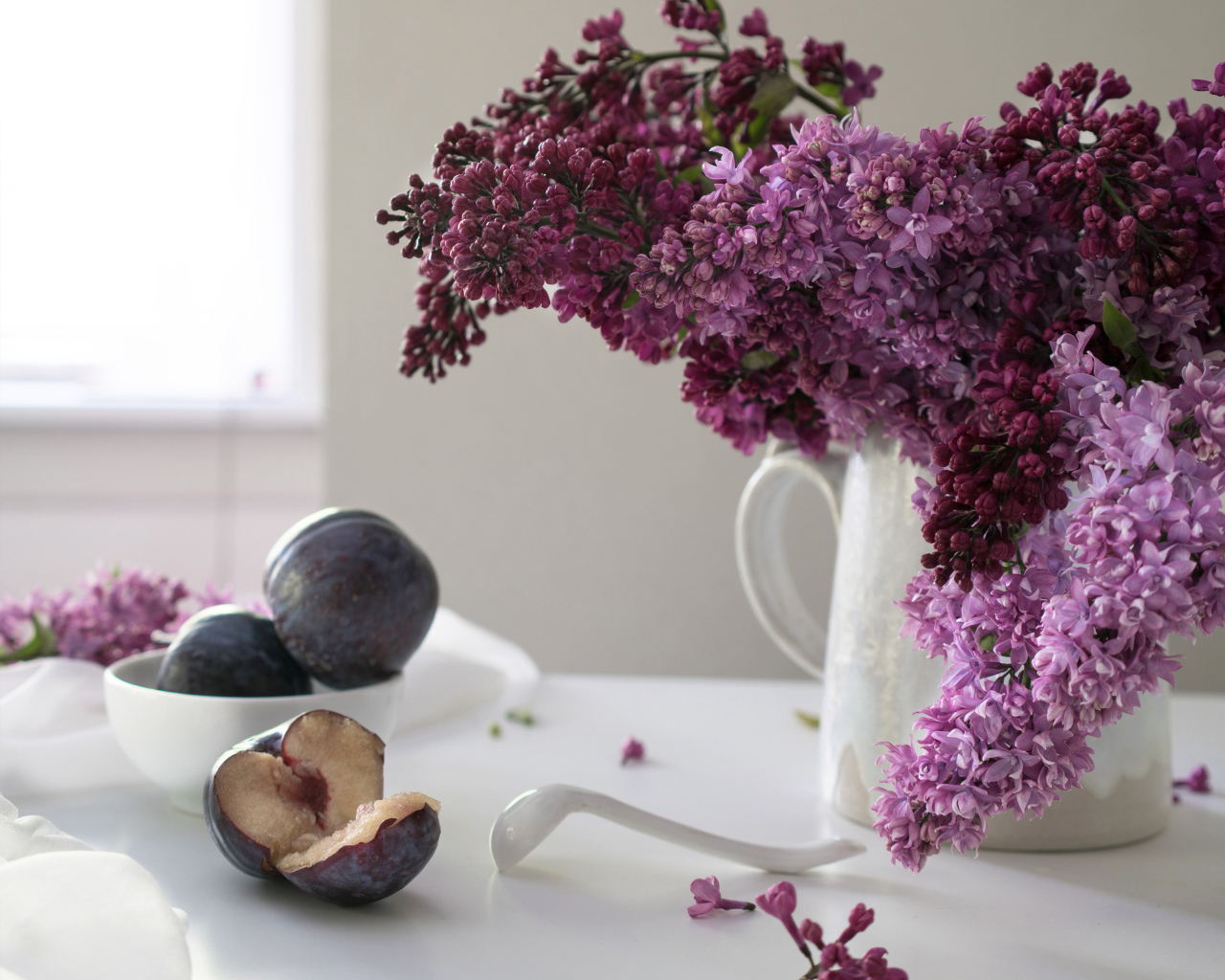 Красивый букет сирени в белой вазе на столе со сливами
