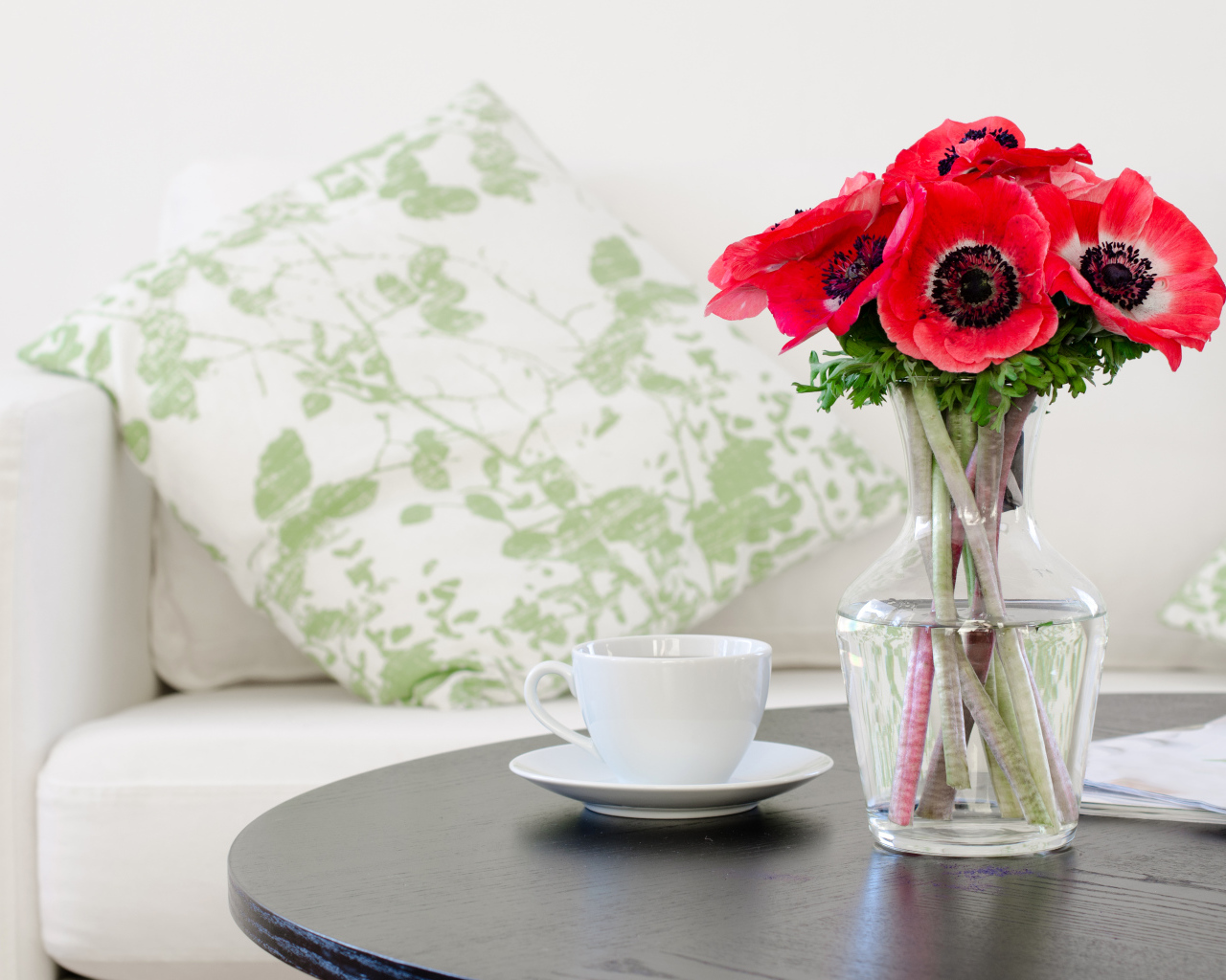 Букет красных цветов анемоны в вазе на столе с белой чашкой