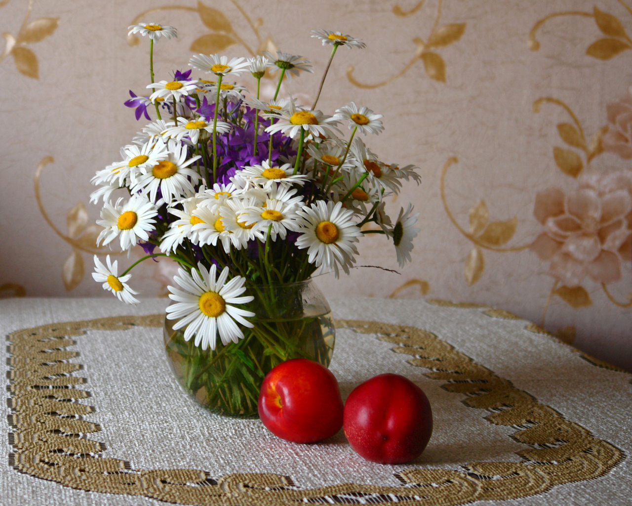 Букет белых полевых ромашек в вазе на столе с розовыми персиками