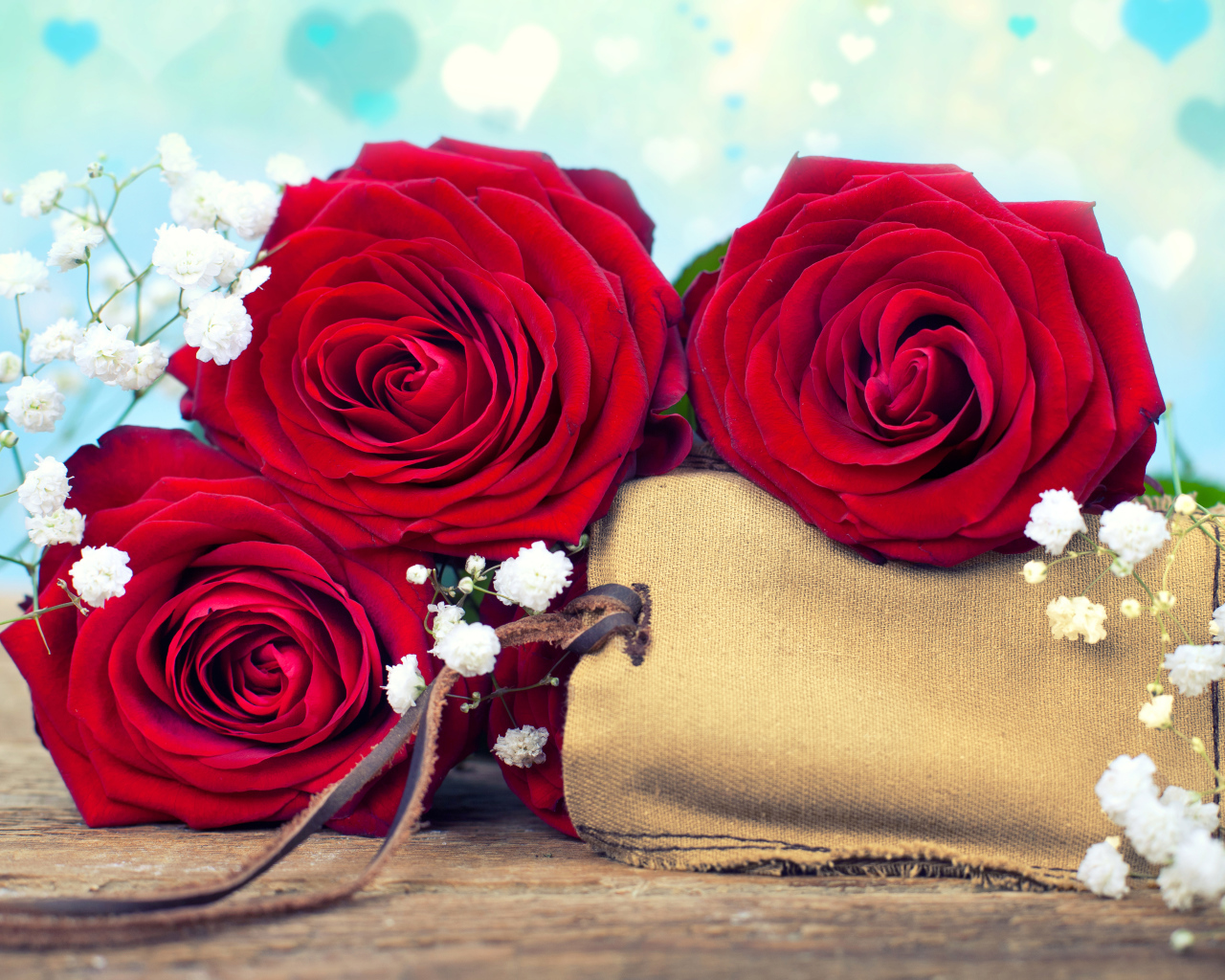 Три больших красных розы с тканевым мешочком