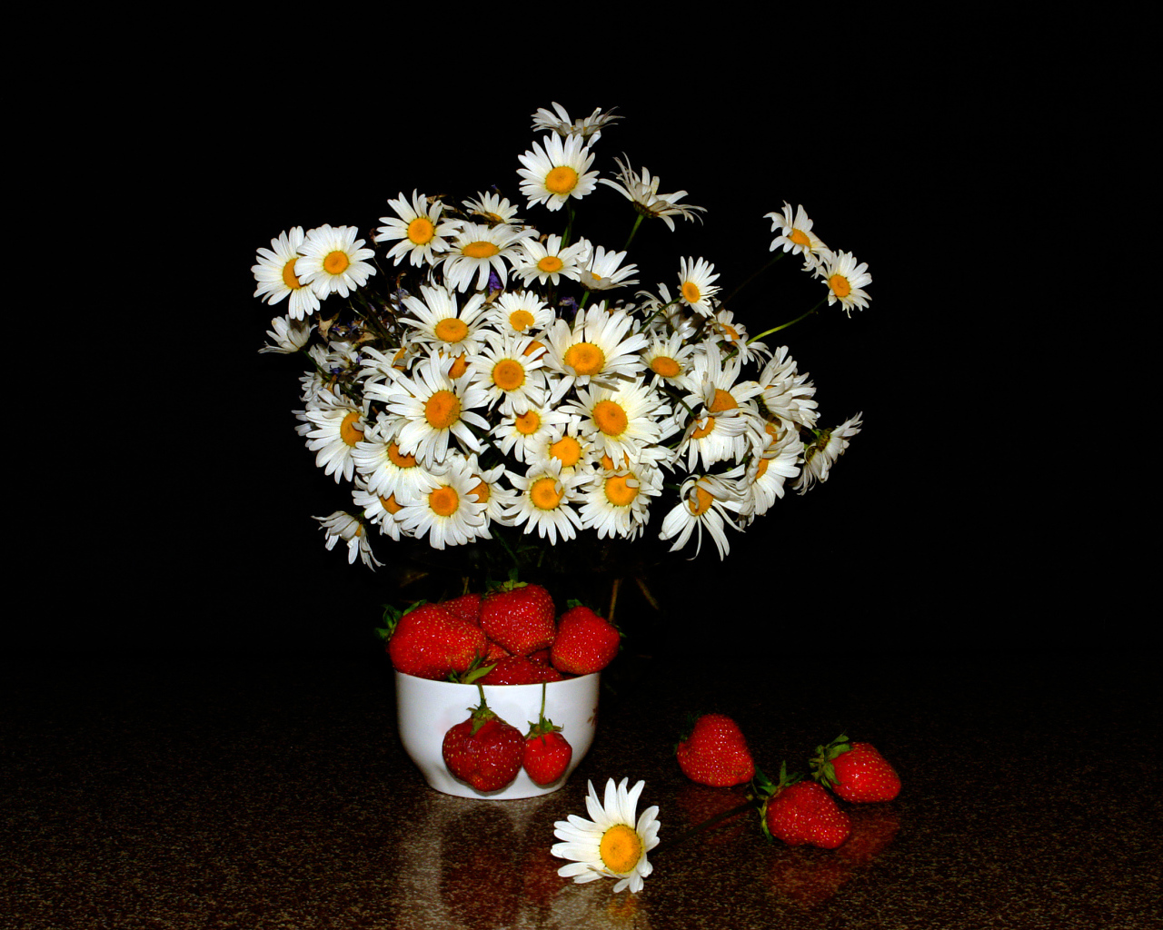 Белые полевые ромашки и клубника на столе на черном фоне
