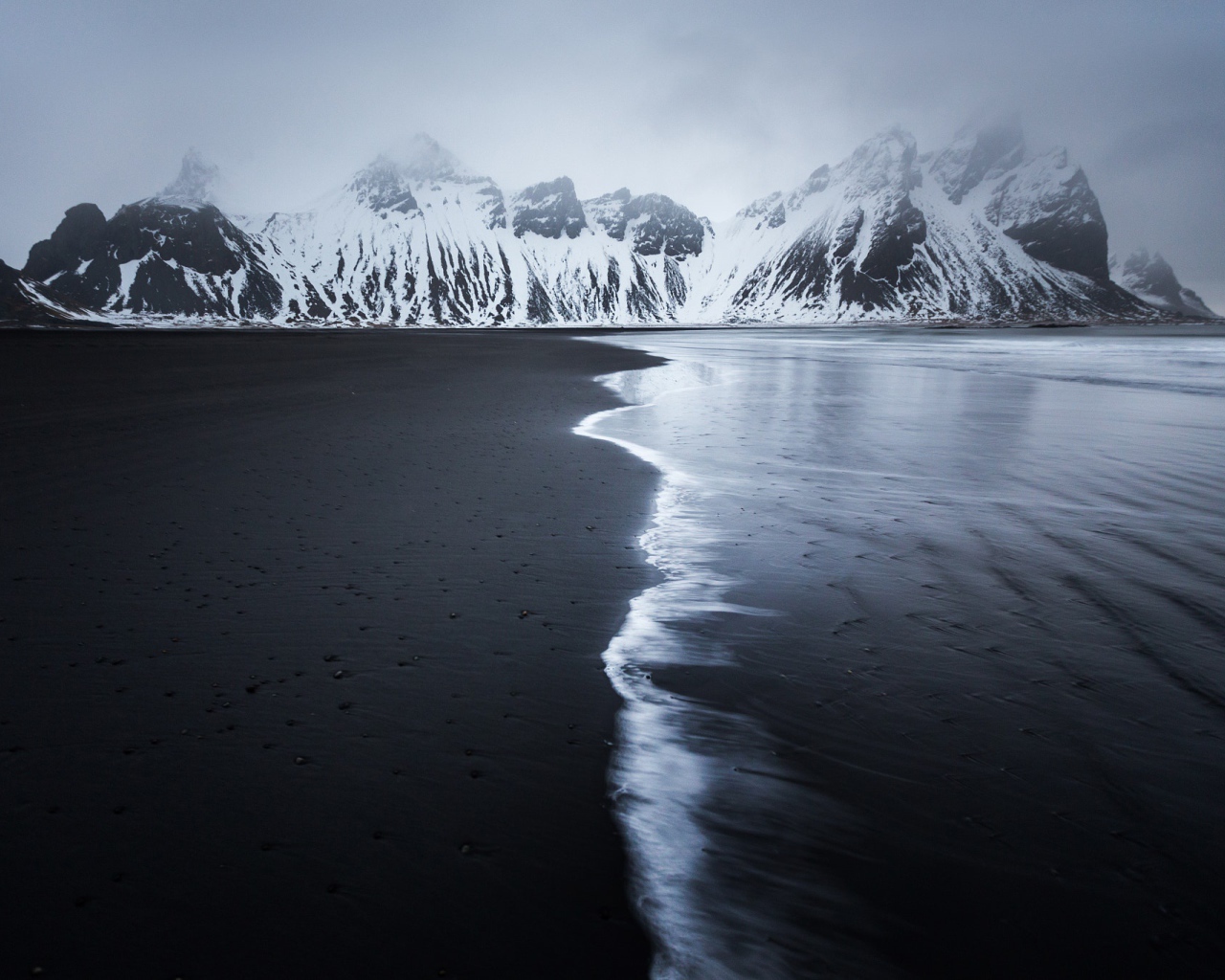 Заснеженные горы у пустынного пляжа