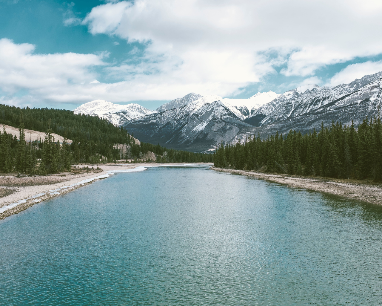 Чистая голубая вода в реке на фоне заснеженных гор 