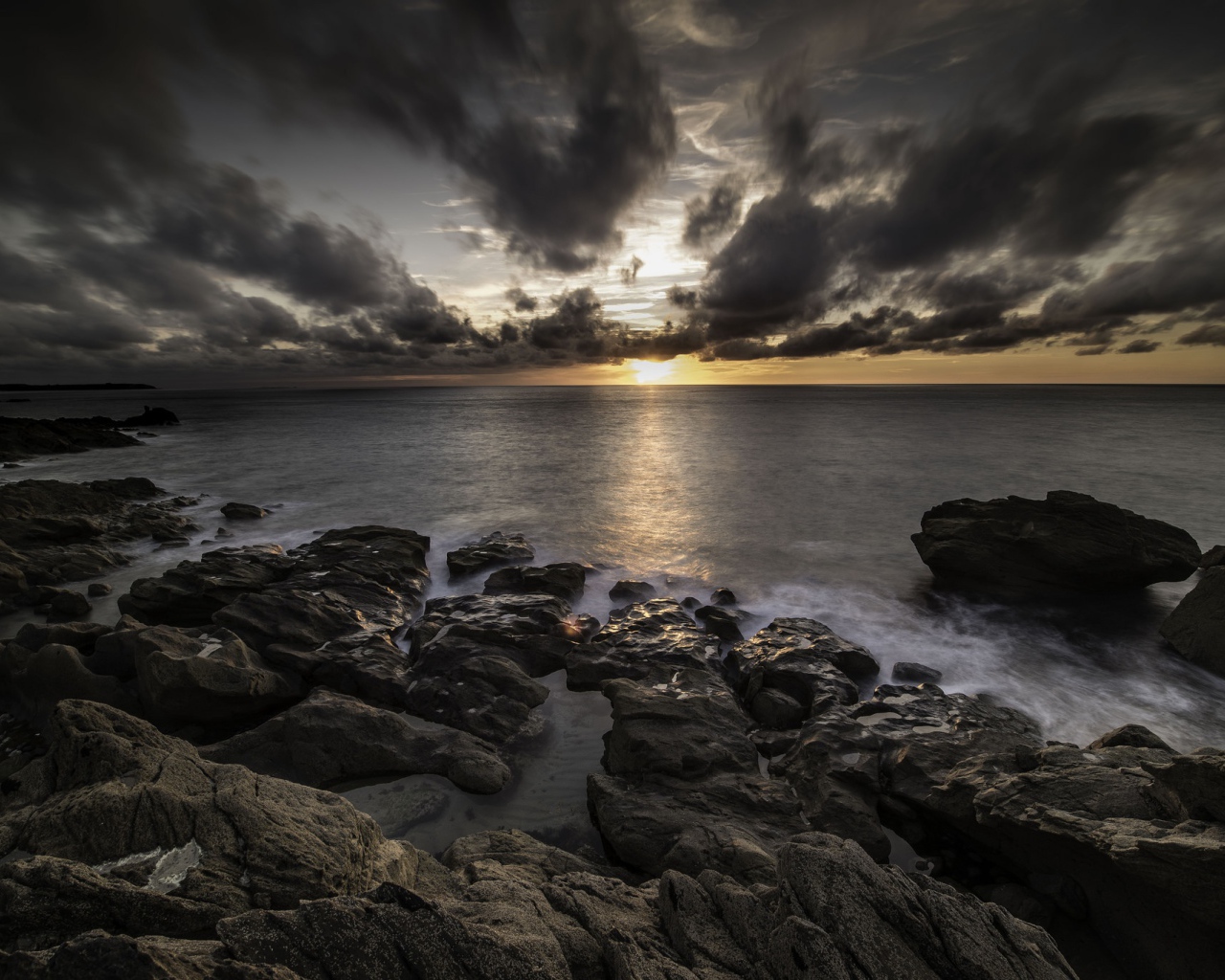 Низкие черные облака на закате в небе над океаном