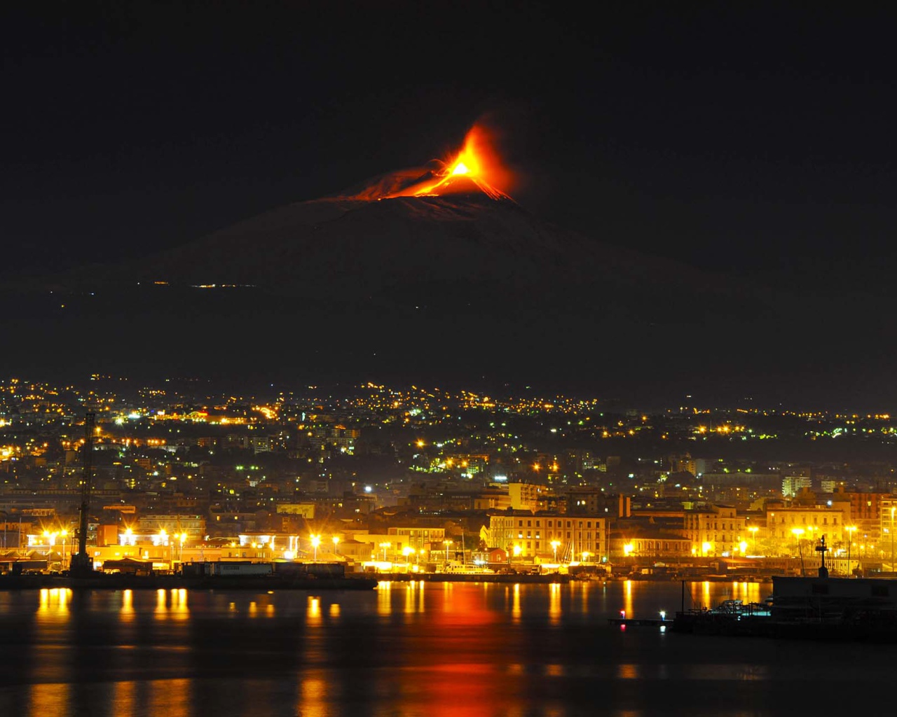 Пробуждение вулкана Этна на фоне ночного города 