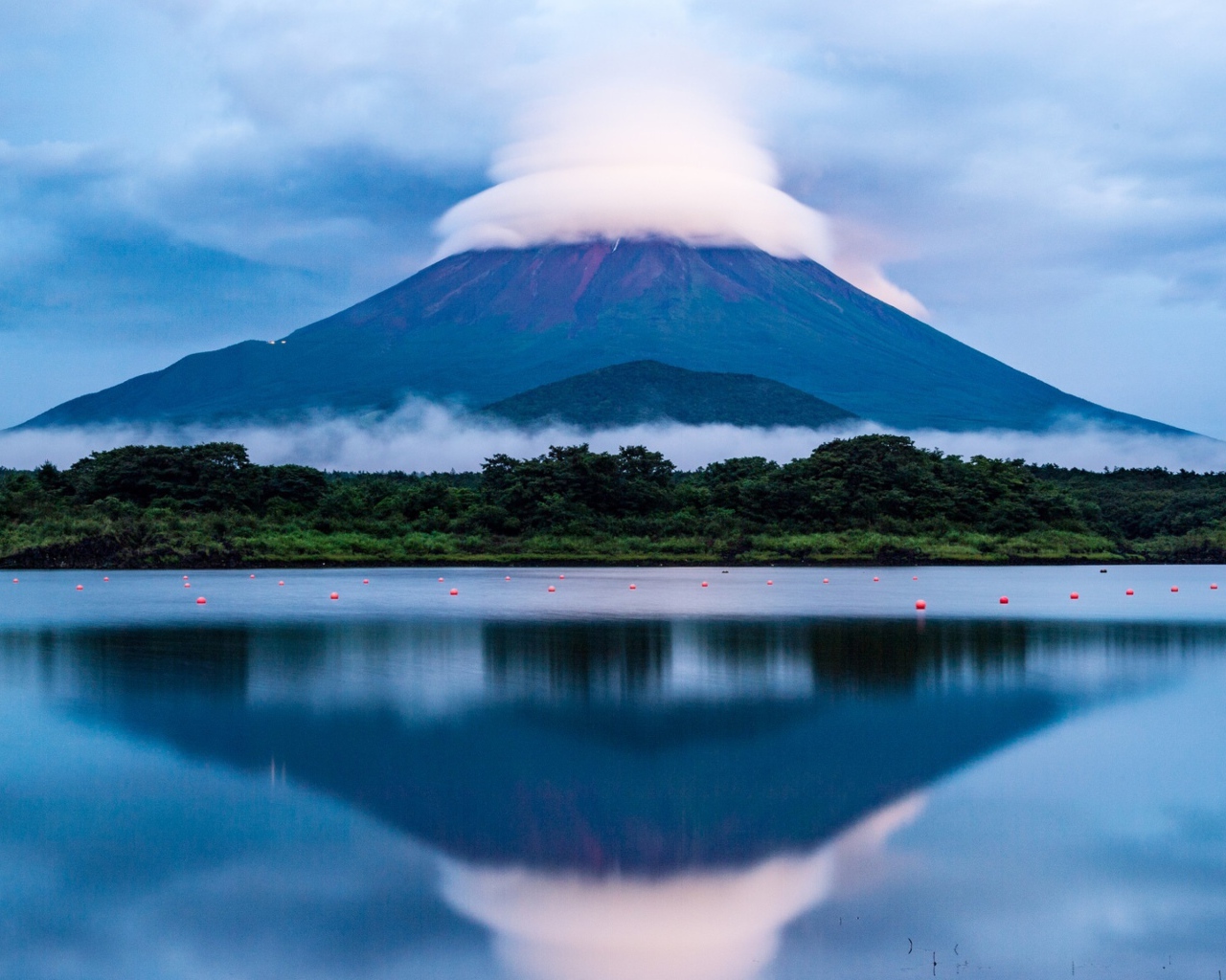 The Fuji volcano in white clouds is reflected in the lake water