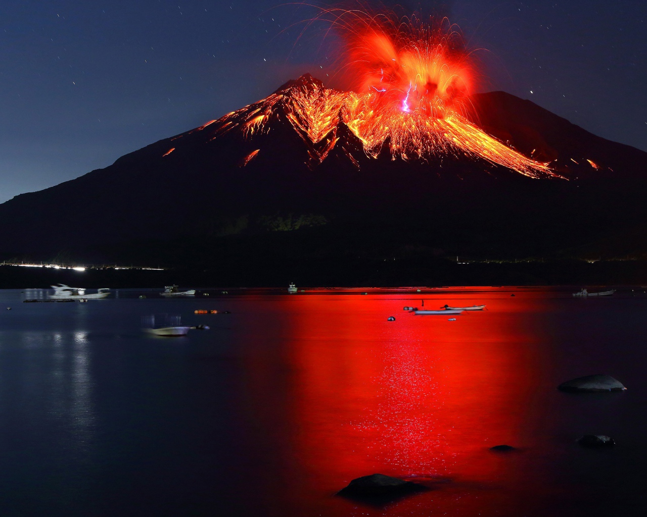 Вулкан Сакурадзима извергается  на фоне воды 