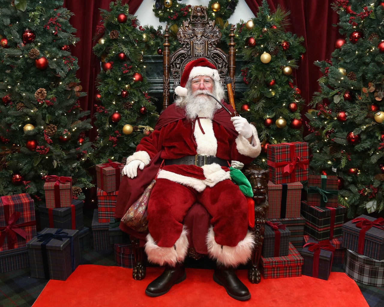 Санта Клаус курит трубку сидя в кресле