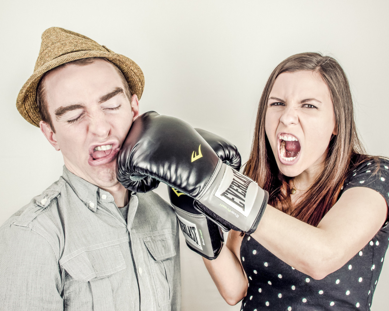 Грозная девушка в боксерских перчатках бьет парня