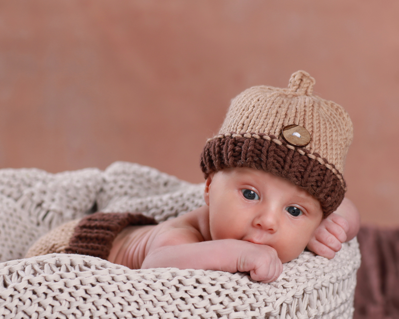 Грудной ребенок в вязаной коричневой шапке