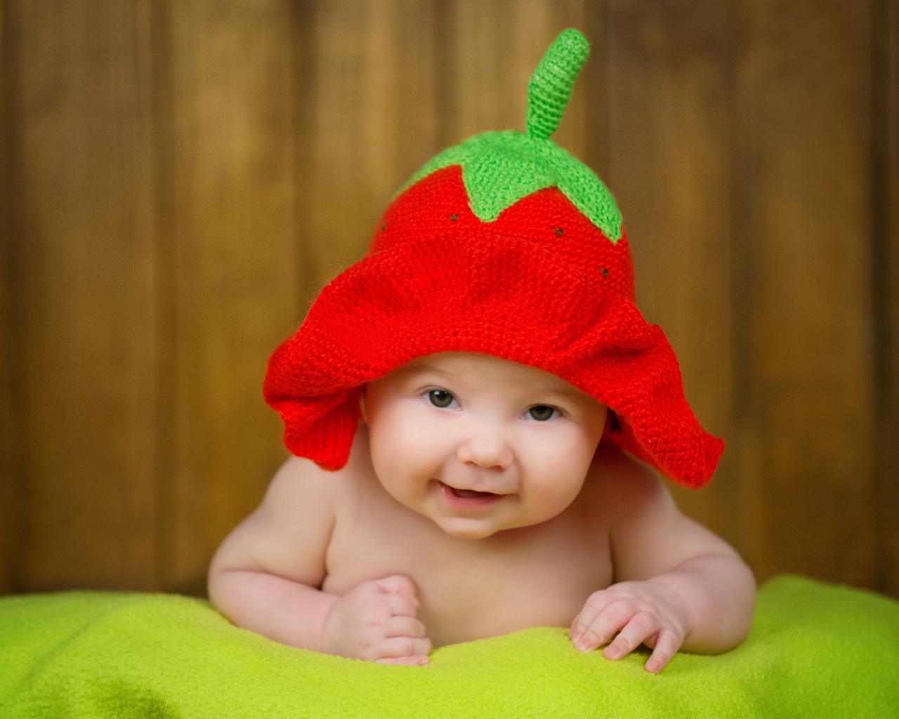 Младенец в забавной шапке клубнике на голове