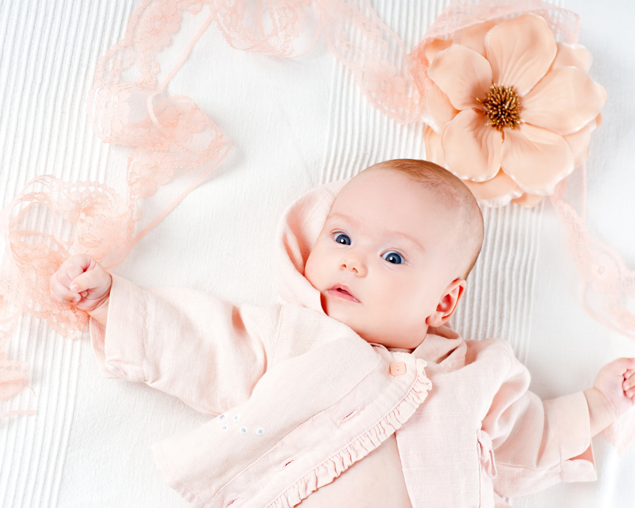 Младенец в розовом наряде с большим цветком у головы