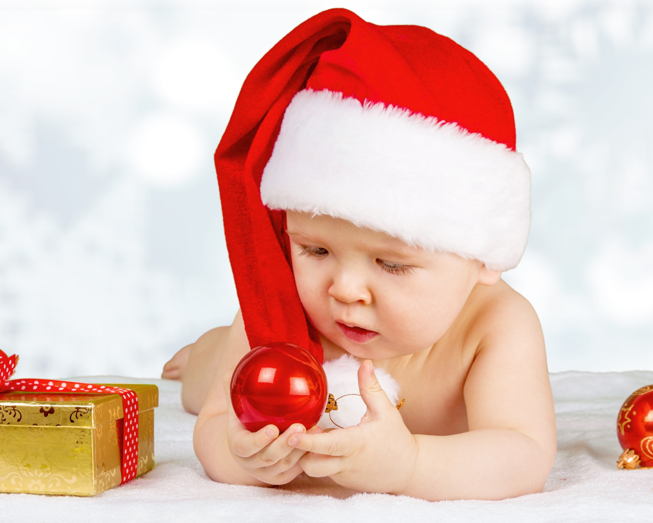 Младенец в красной новогодней шапке с елочными шарами на новый год