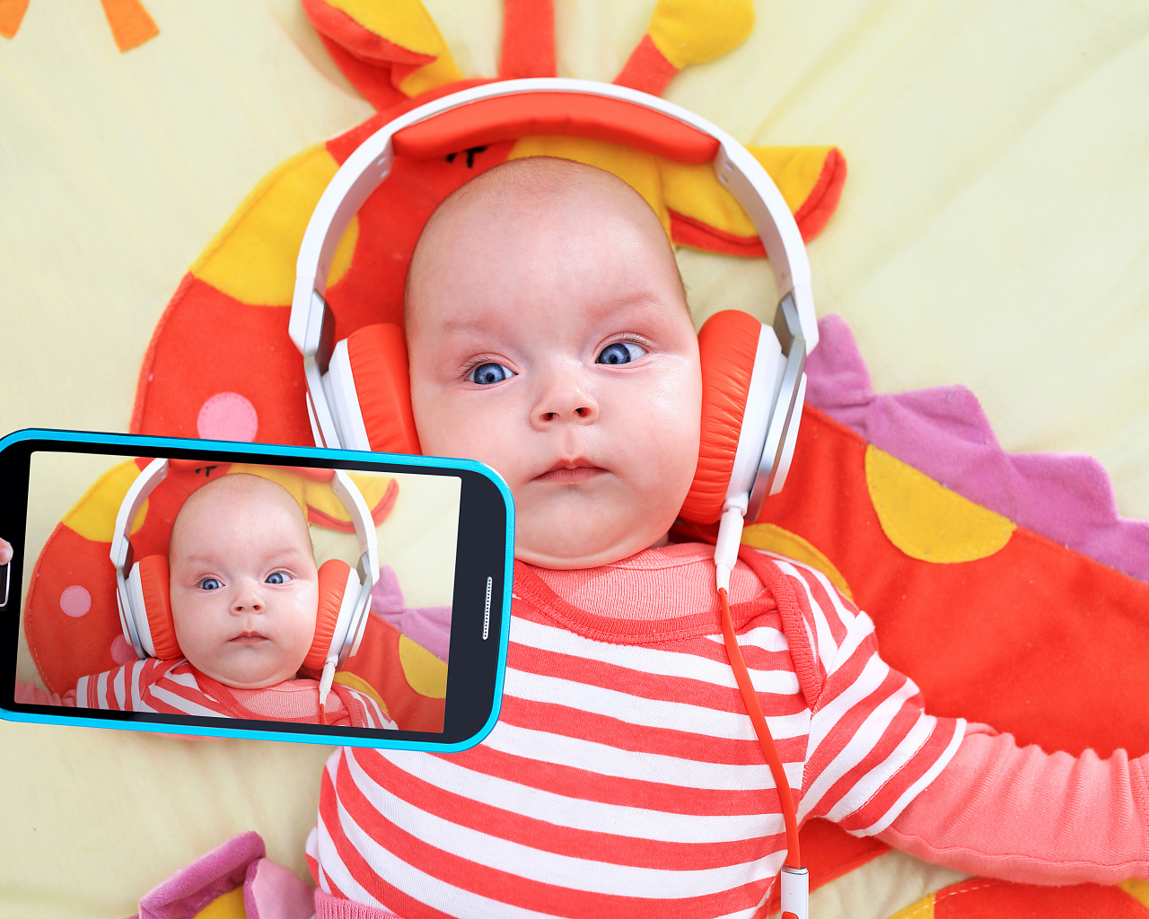 Младенец в оранжевых наушниках делает селфи
