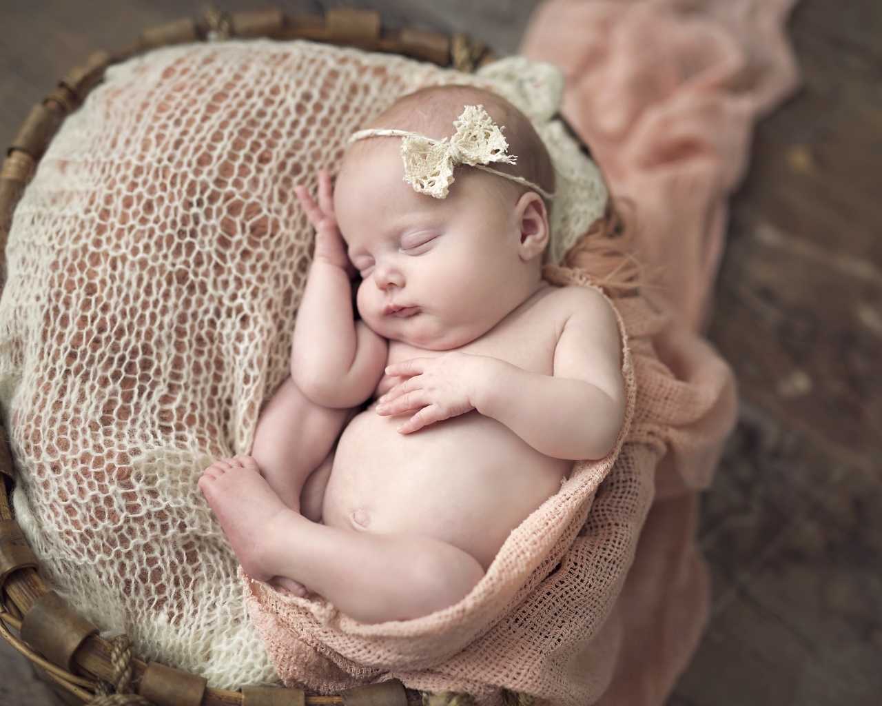 Грудной ребенок с бантиком на голове спит в корзине