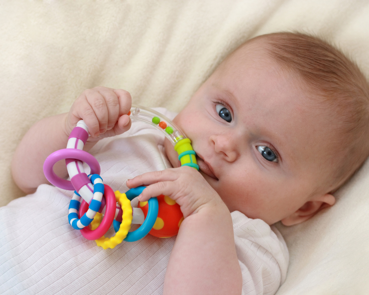 Грудной ребенок с погремушкой в руках