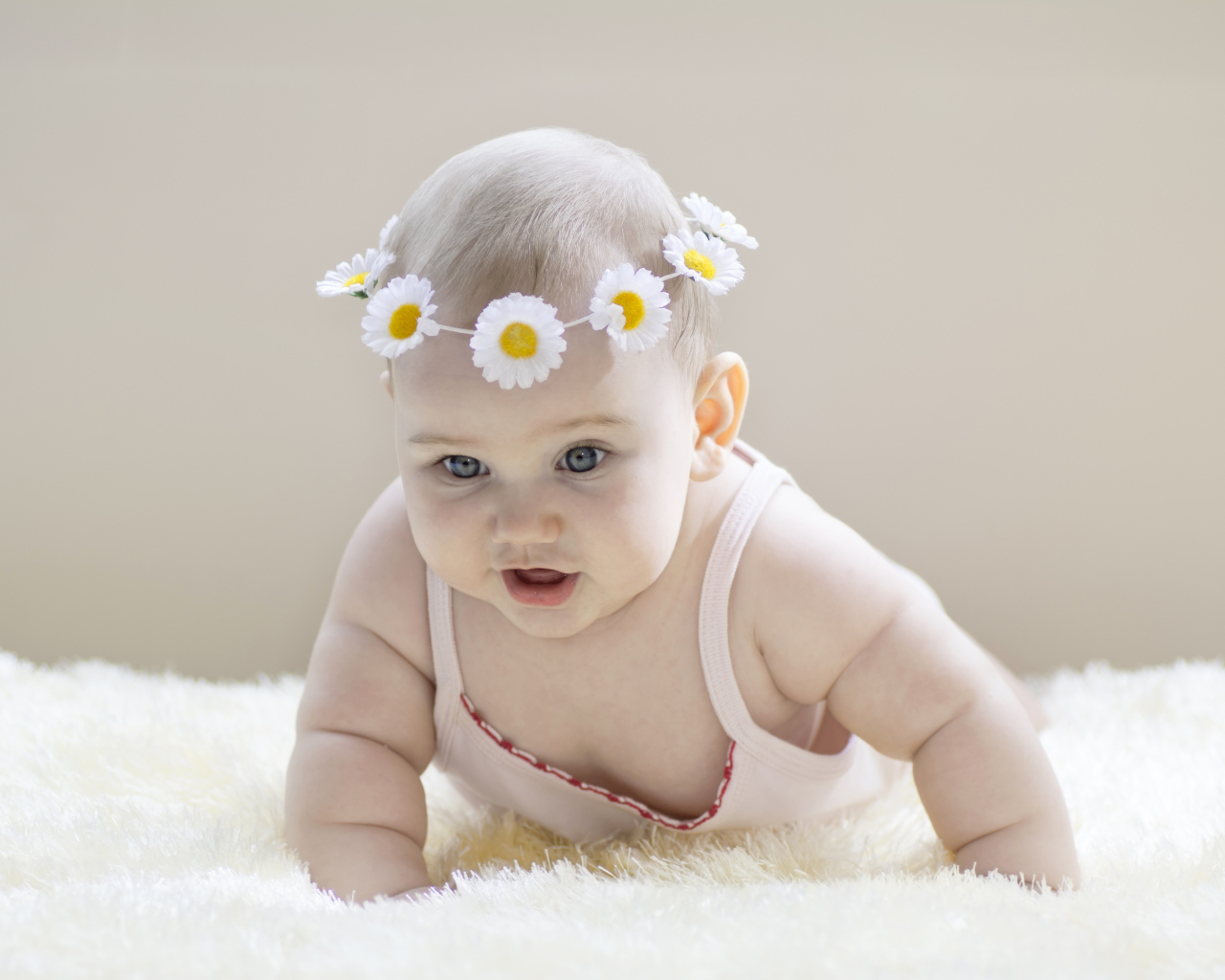 Грудной ребенок с венком из белых ромашек на голове