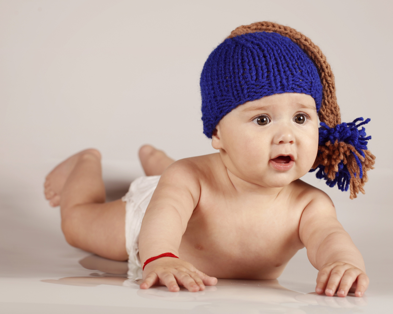 Грудной кареглазый ребенок в вязаной шерстяной шапке