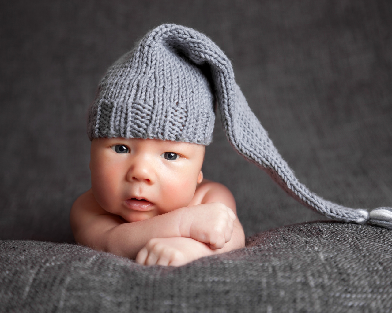 Милый младенец в большой серой вязаной шапке