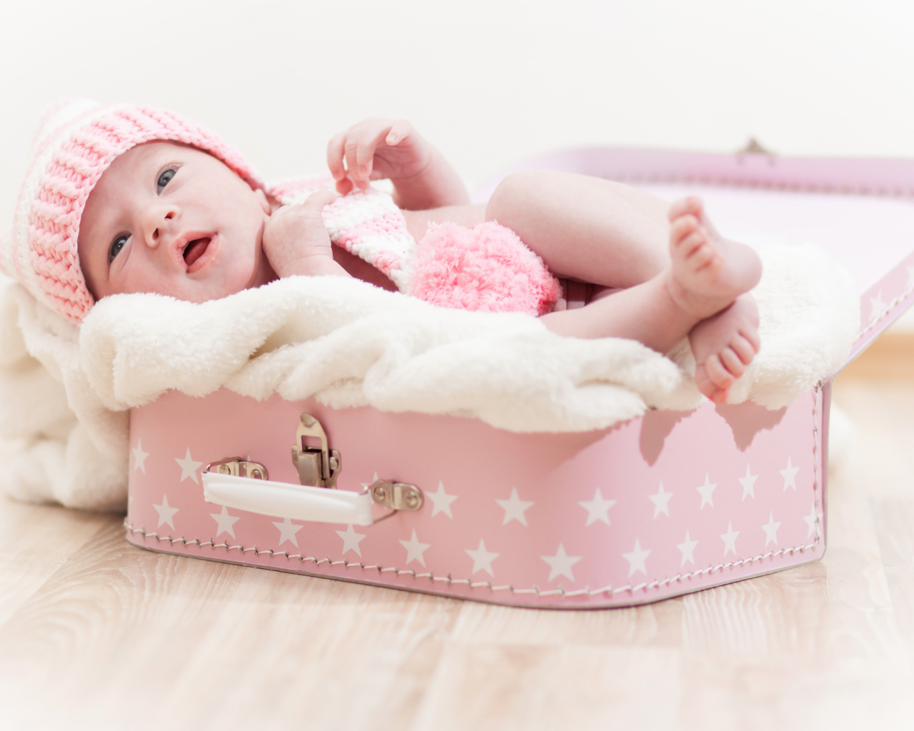 Милый младенец лежит в розовом чемодане