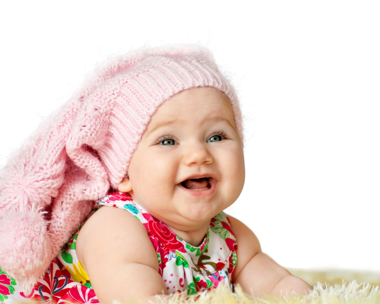 Милая маленькая улыбающаяся девочка в большой розовой шапке