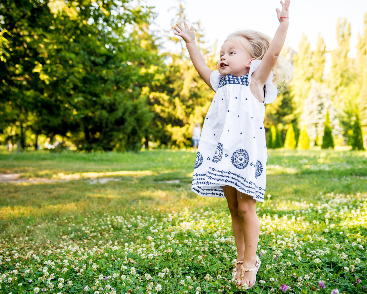 Девочка в красивом платье гуляет на зеленом лугу