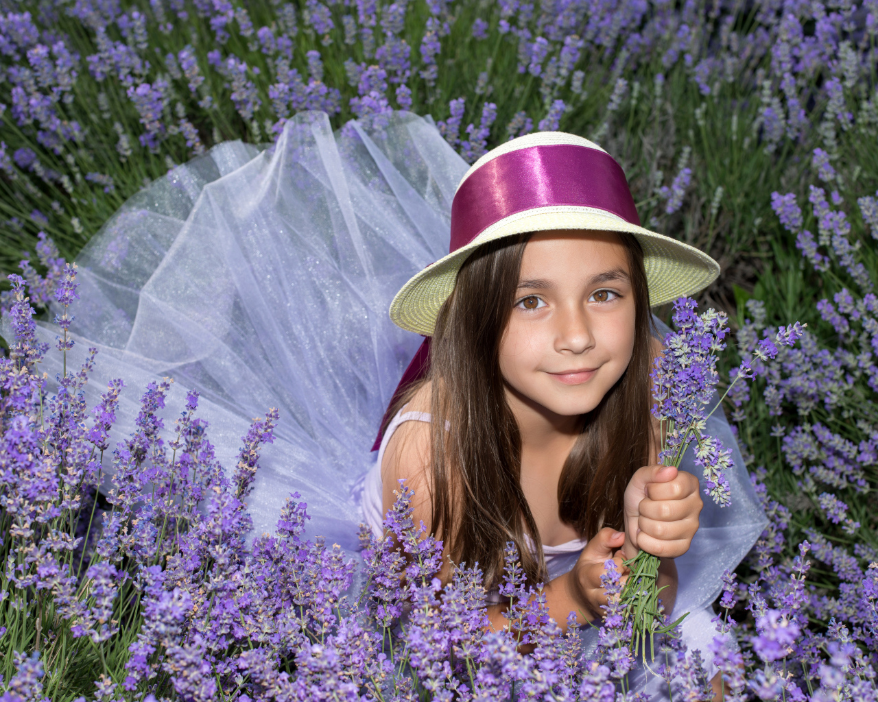 Девочка в шляпе лежит в фиолетовых цветах лаванды