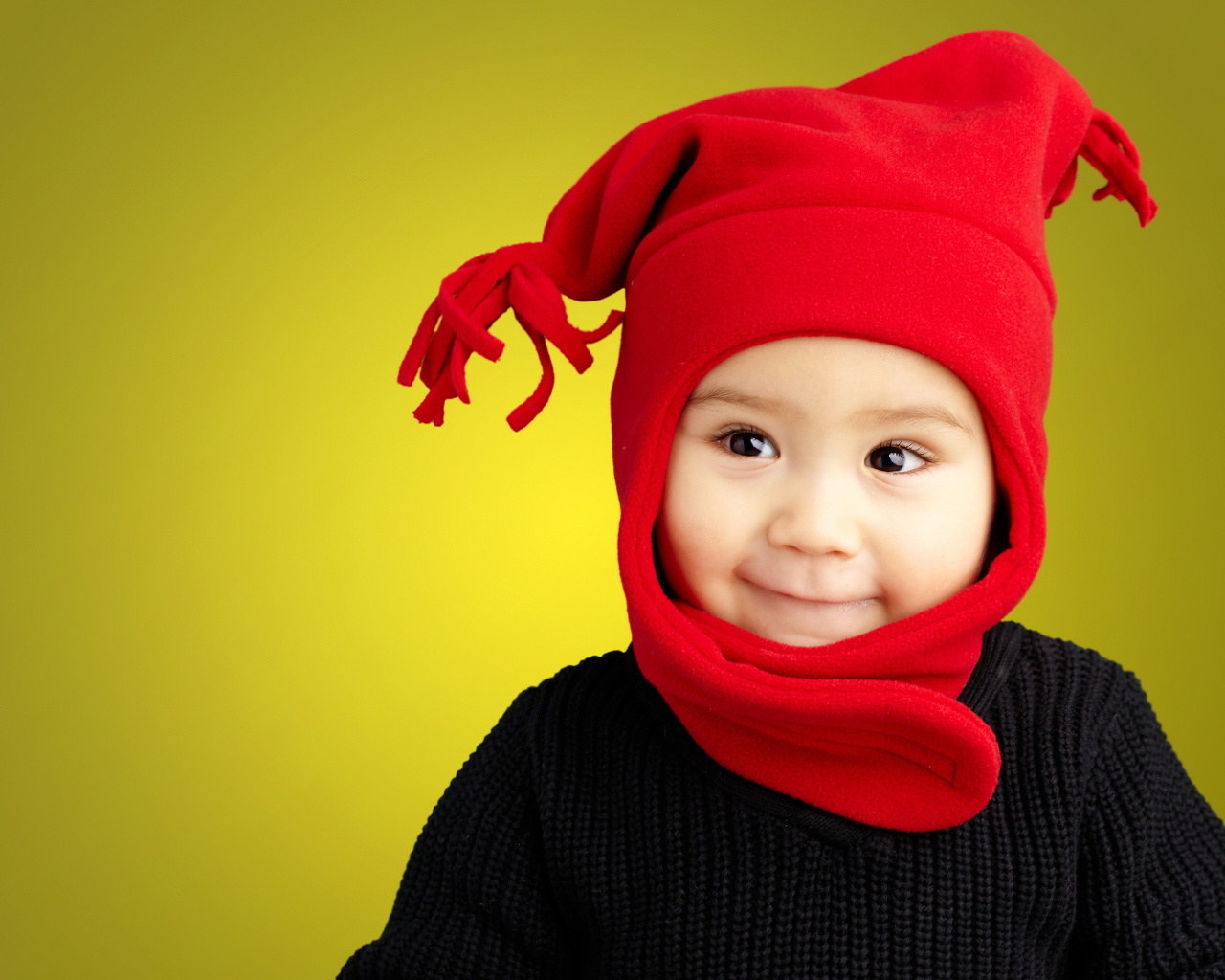 Маленький мальчик в красной шапке и в черном свитере