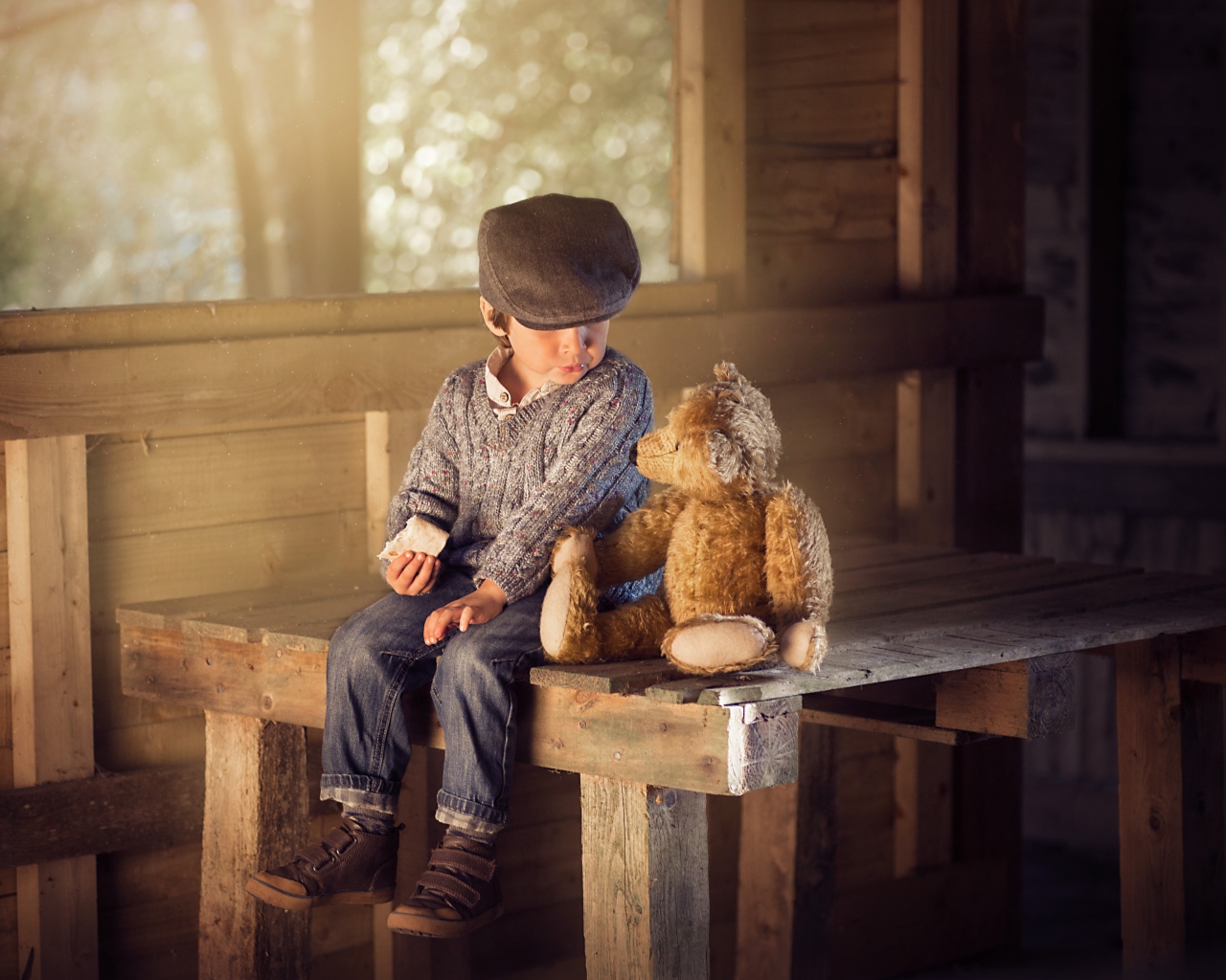 Маленький мальчик сидит на деревянном столе с медвежонком Тедди