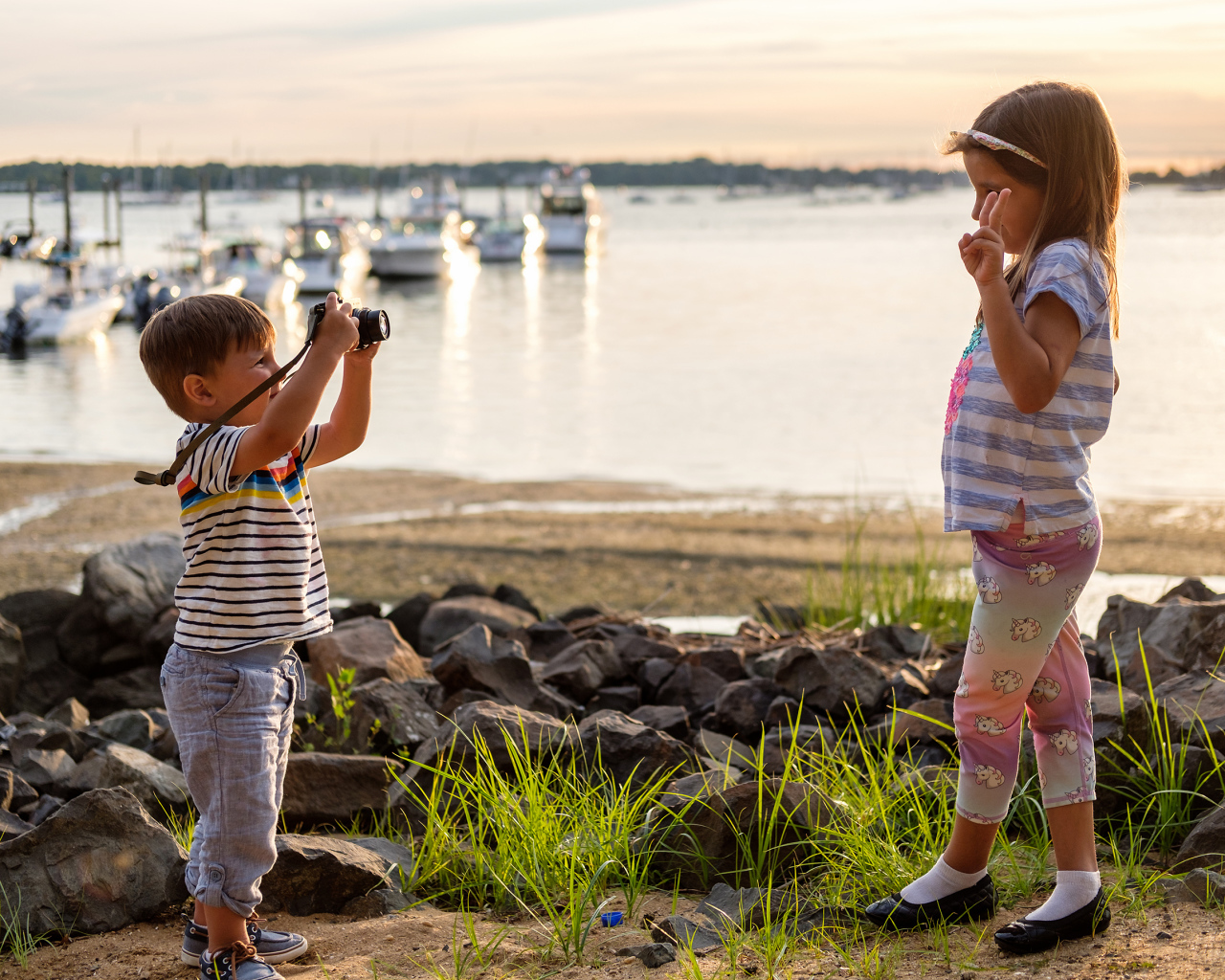 Маленький мальчик фотографирует девочку на берегу