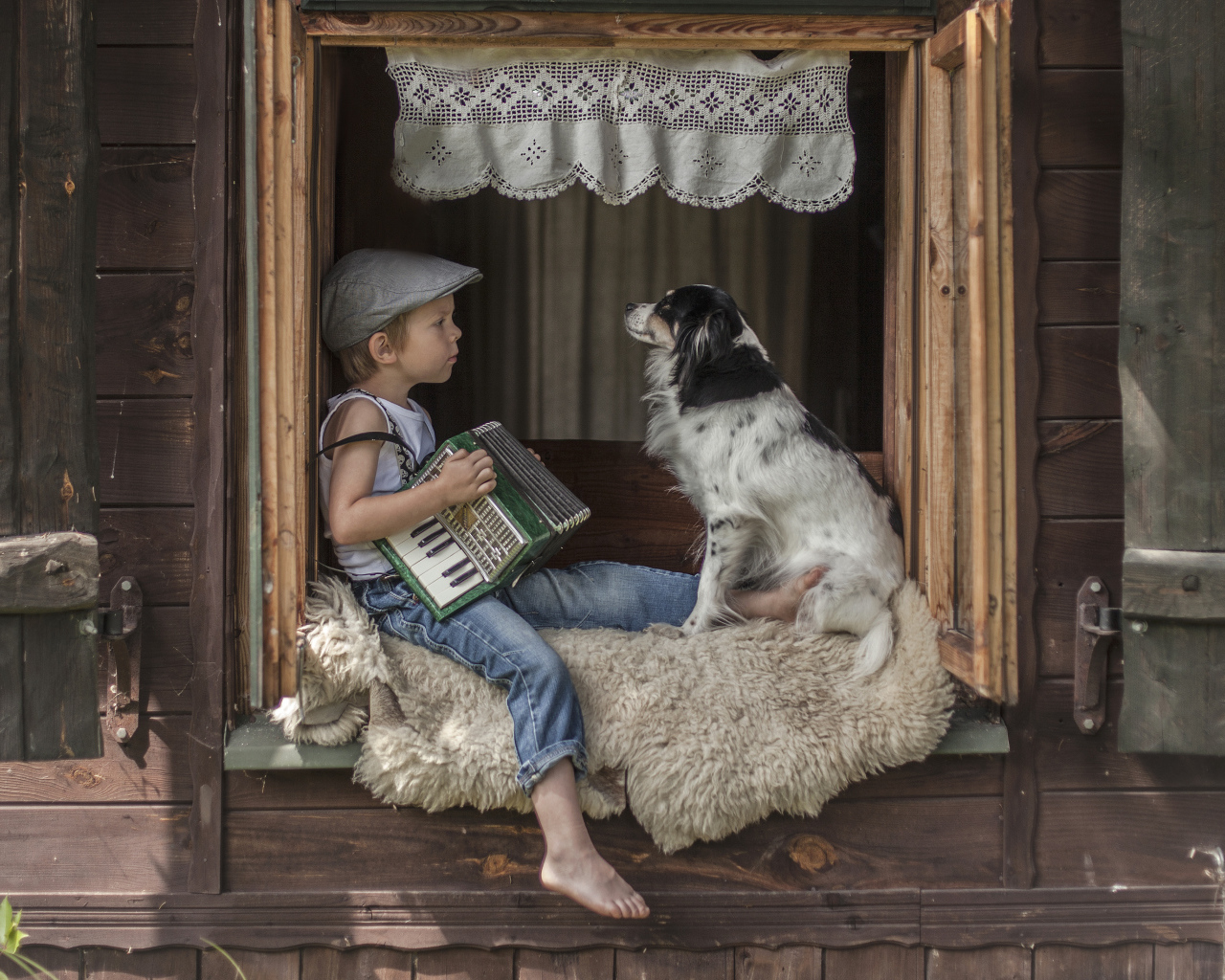Маленький мальчик с гармошкой сидит на подоконнике с собакой