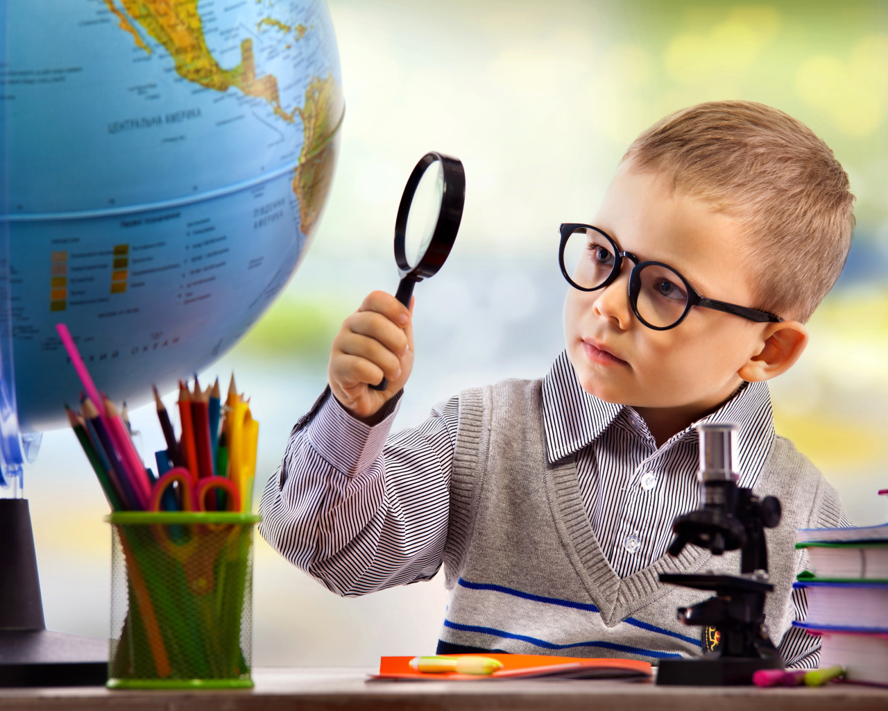 Маленький мальчик в очках исследует глобус