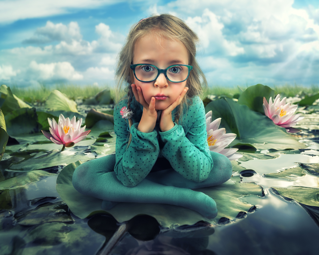 Маленькая девочка в зеленом костюме сидит на листе водяной лилии