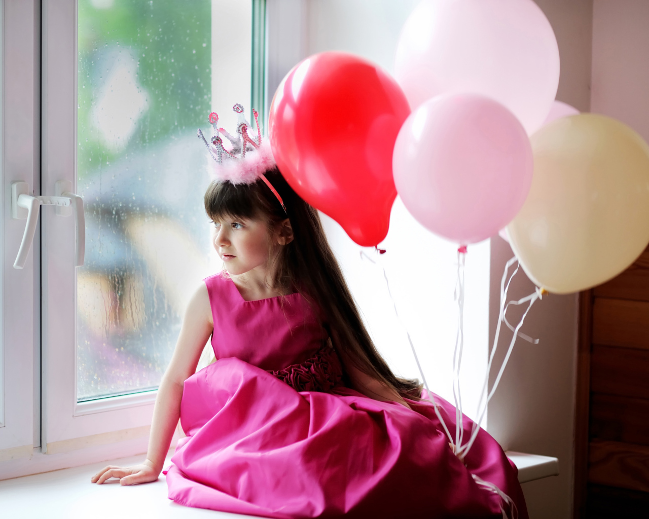 Маленькая девочка в костюме принцессы сидит на окне