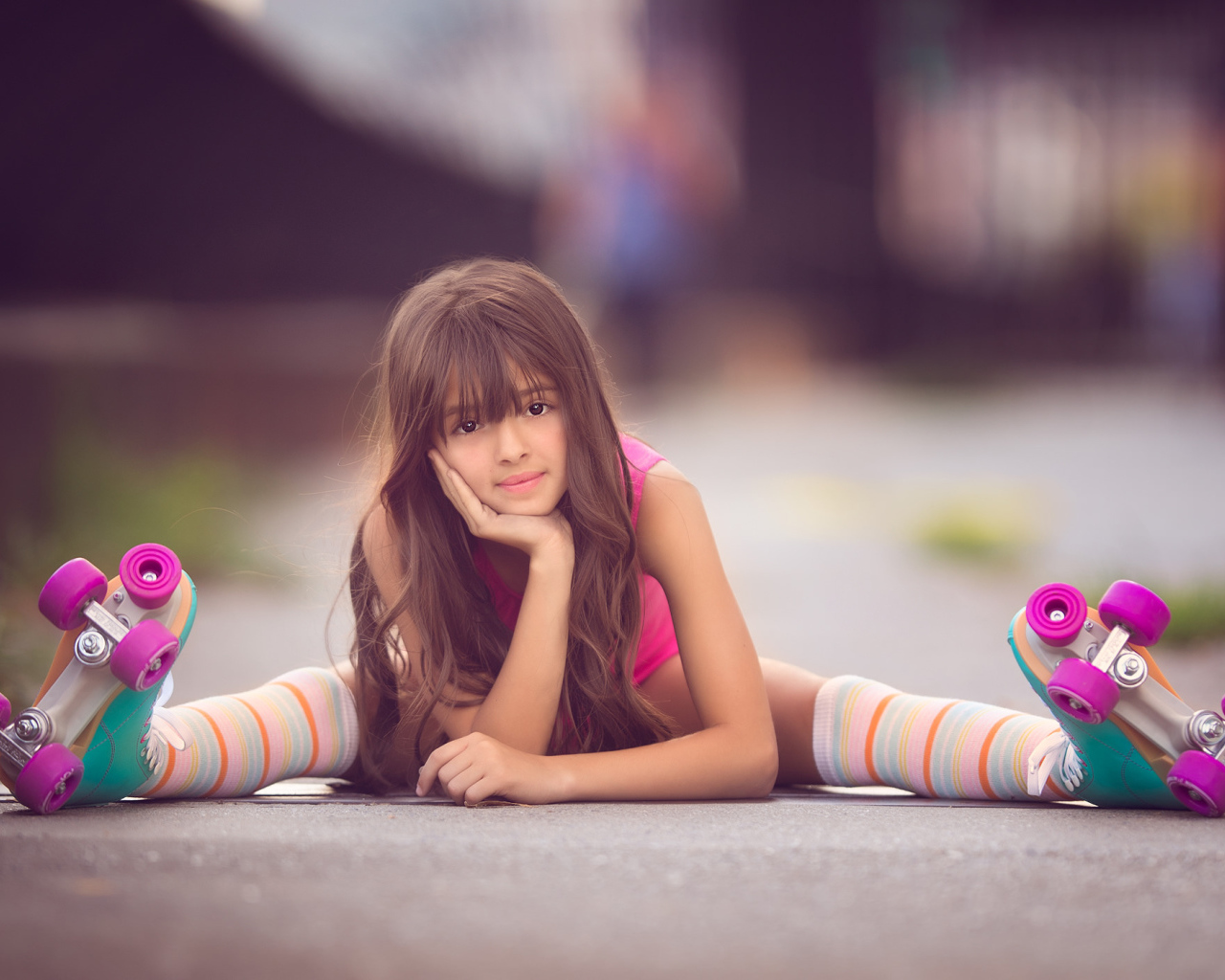 Маленькая девочка сидит на дороге в роликах