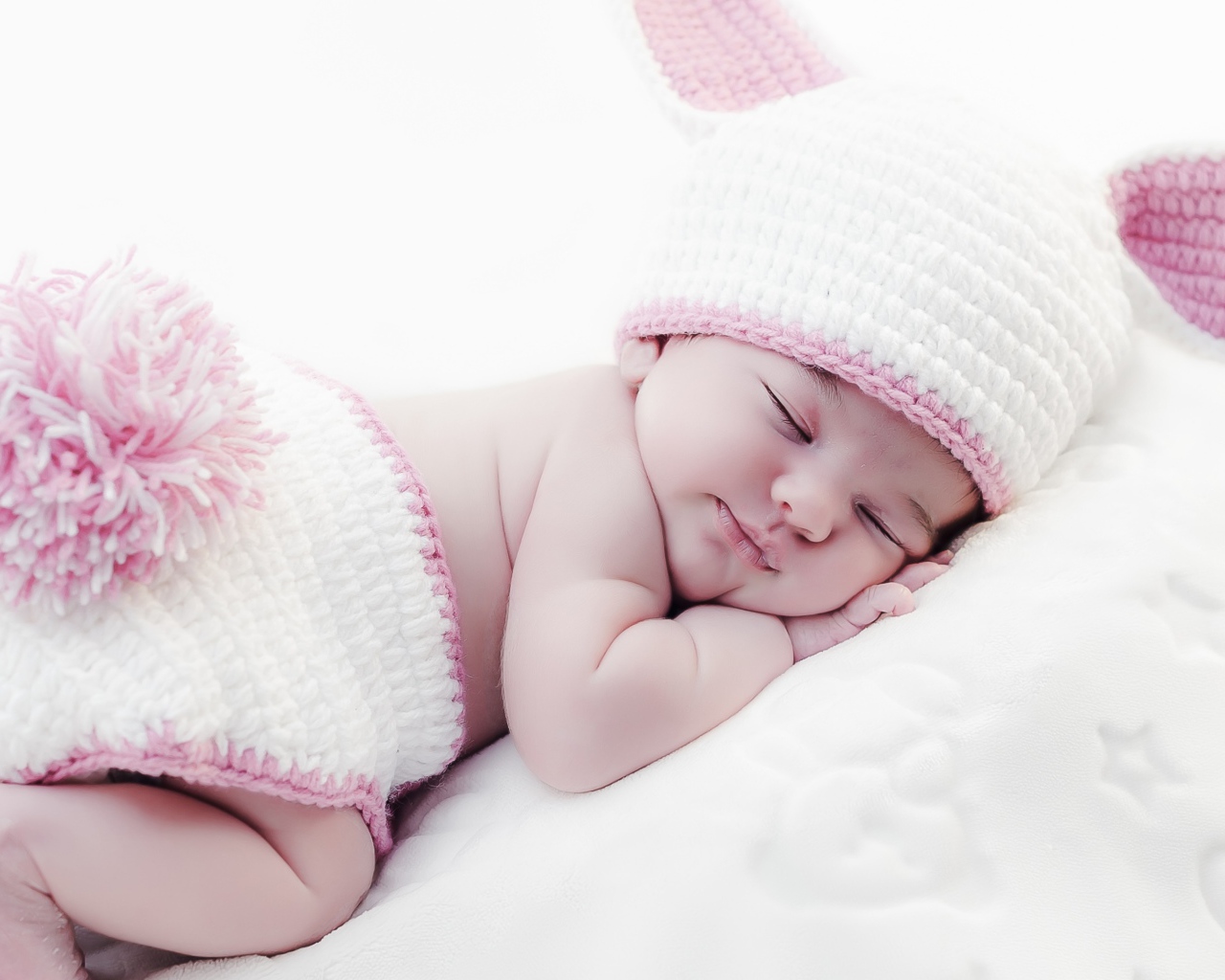 Маленький спящий ребенок в вязаном костюме зайчика