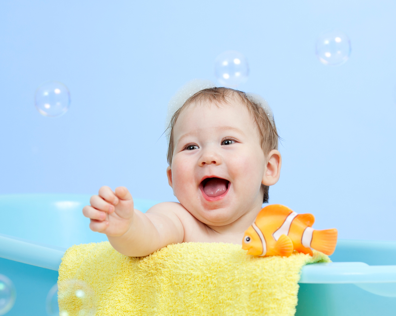 Веселый малыш купается в ванной с игрушечной рыбкой