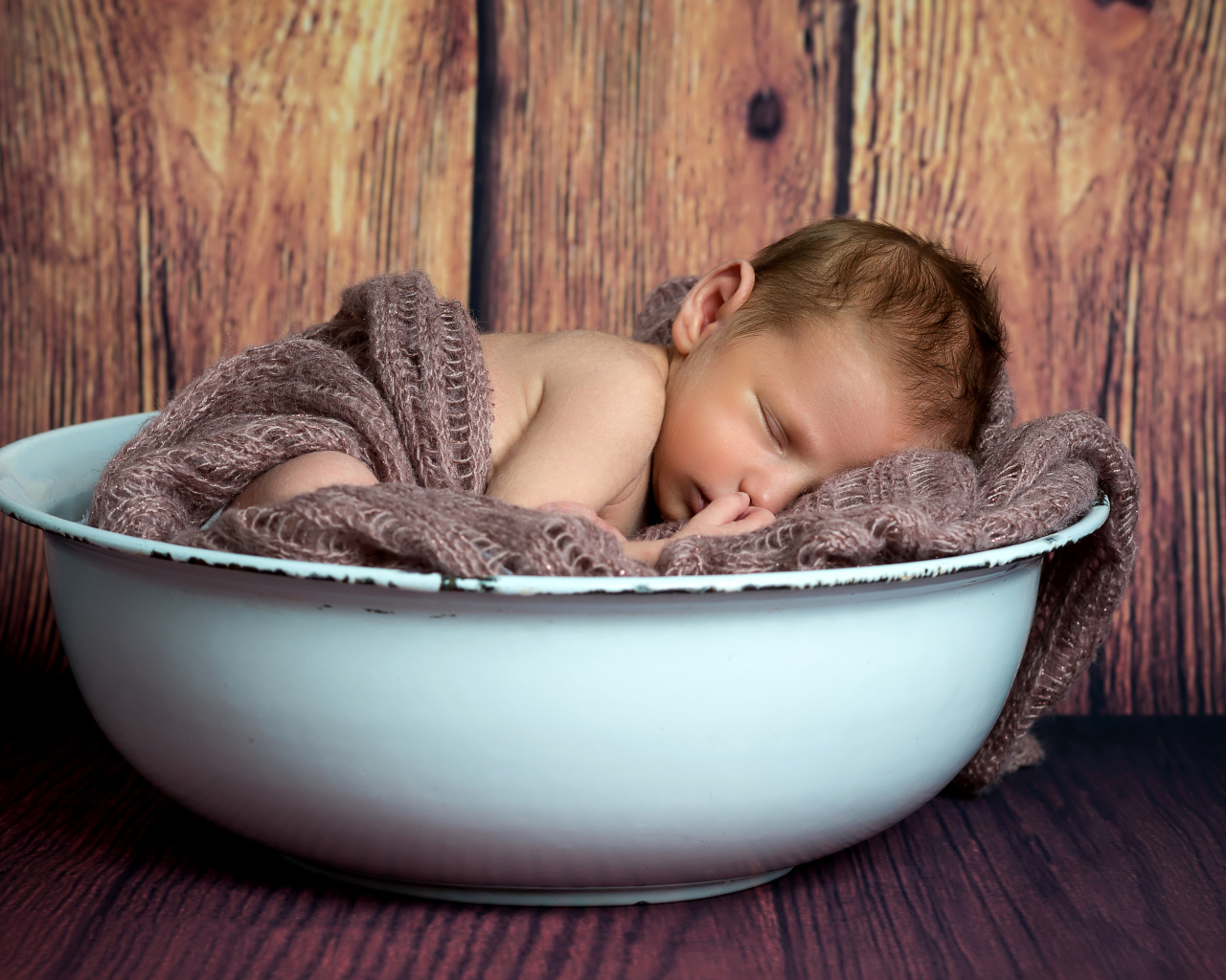 Новорожденный ребенок спит в белой миске