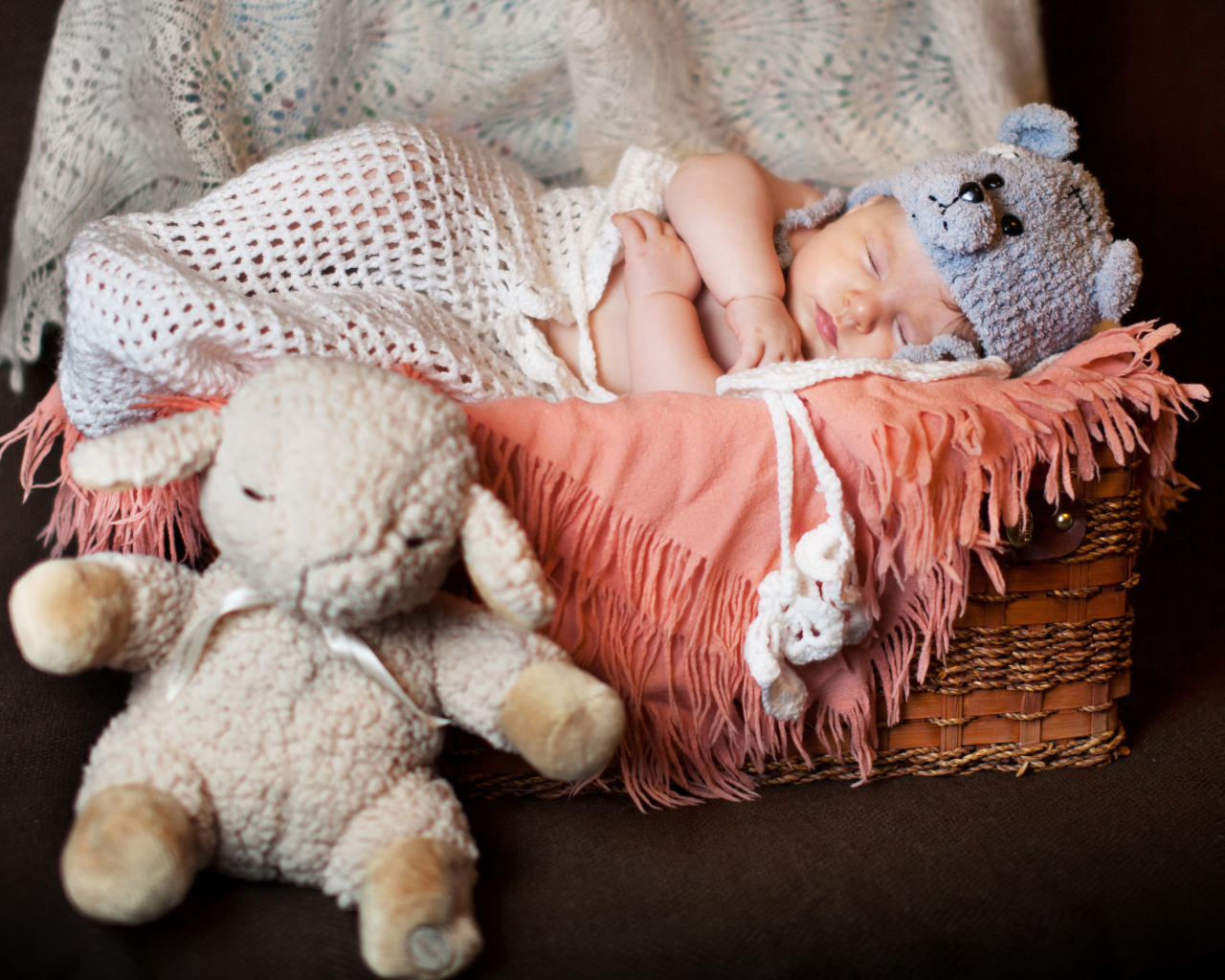 Спящий грудной ребенок в забавной шапке с мягкой игрушкой