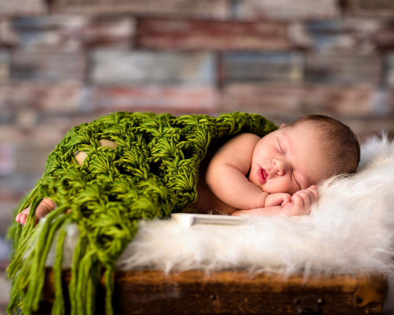 Спящий младенец под зеленым вязаным пледом