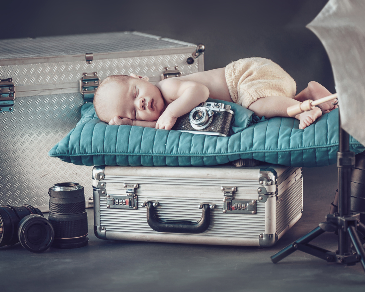 Спящий младенец с фотоаппаратом спит на чемодане