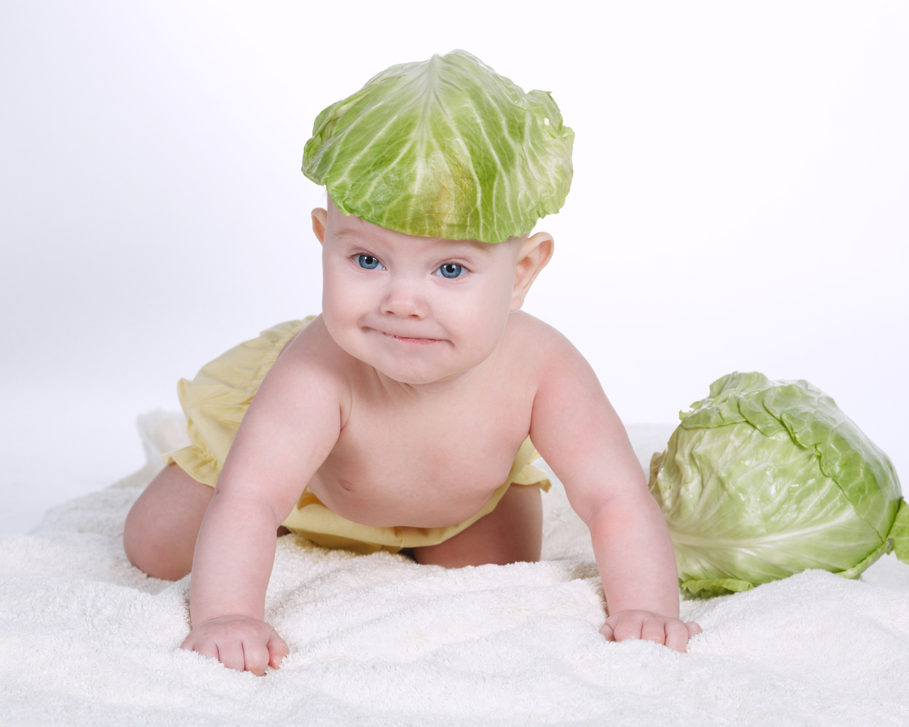 Маленький грудной ребенок с капустным листом на голове
