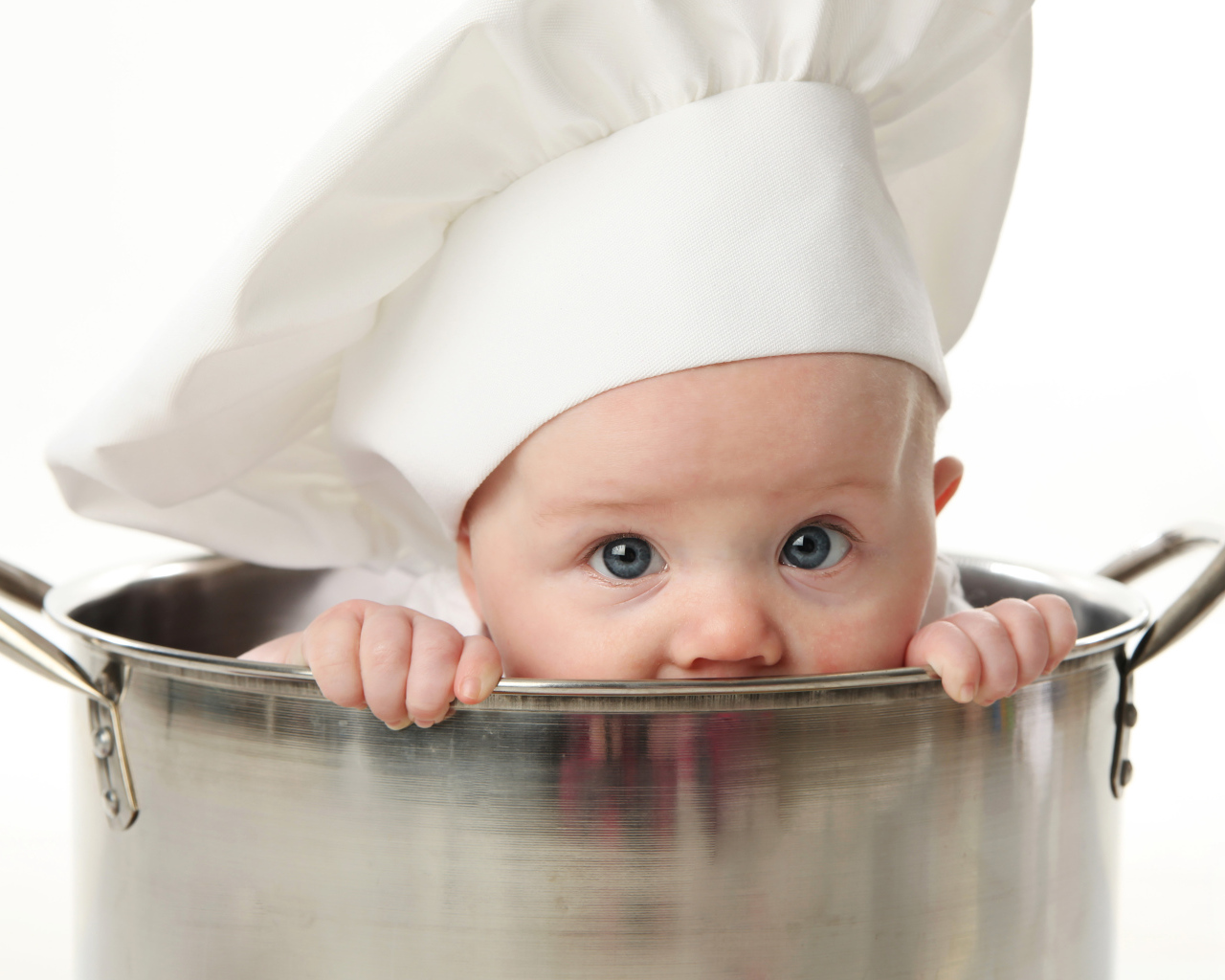 Маленький ребенок сидит в большой железной кастрюле