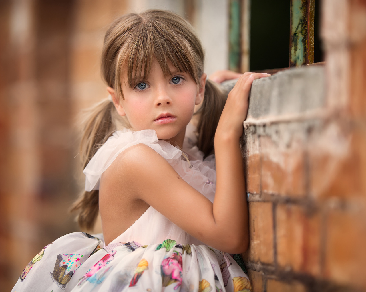 Милая девочка с серьезным взглядом стоит у стены