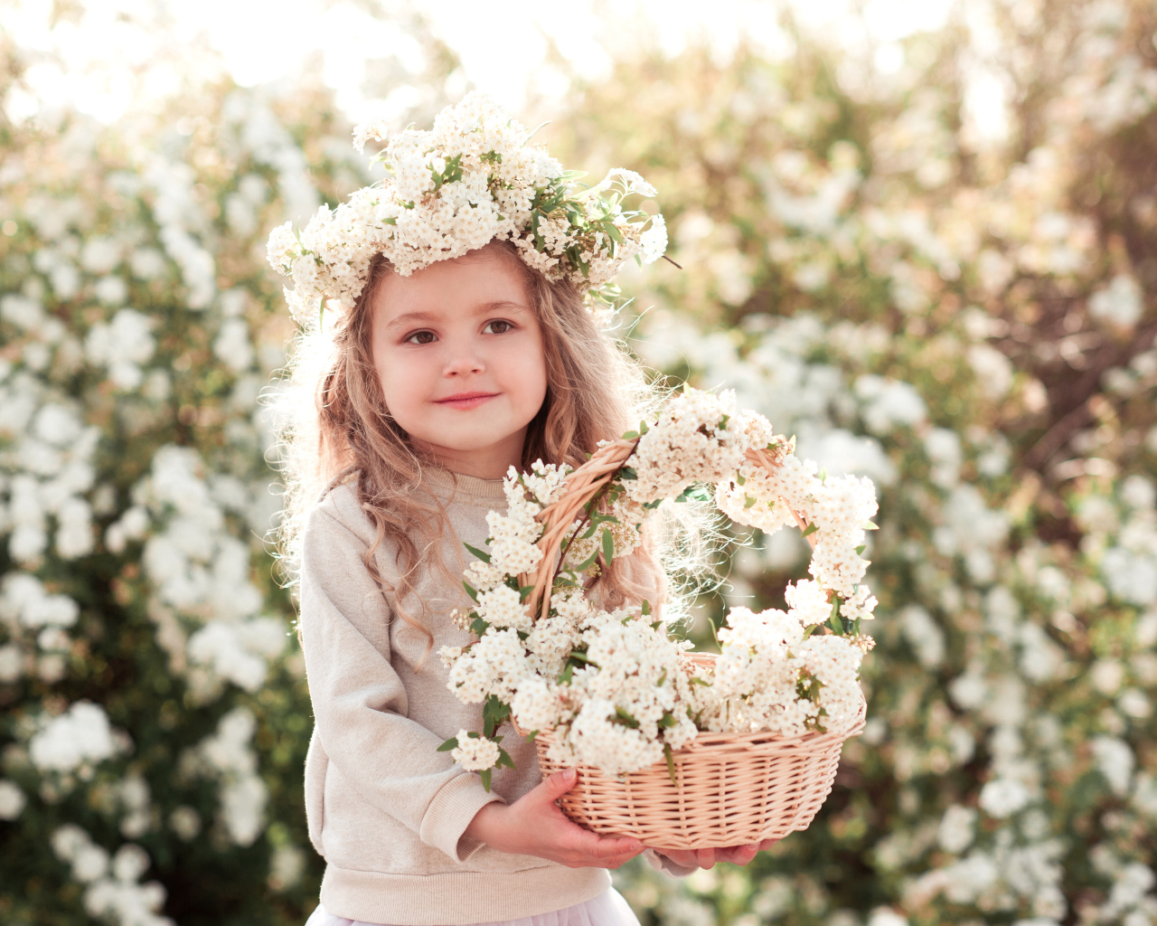 Милая маленькая девочка с венком на голове и корзиной белых цветов
