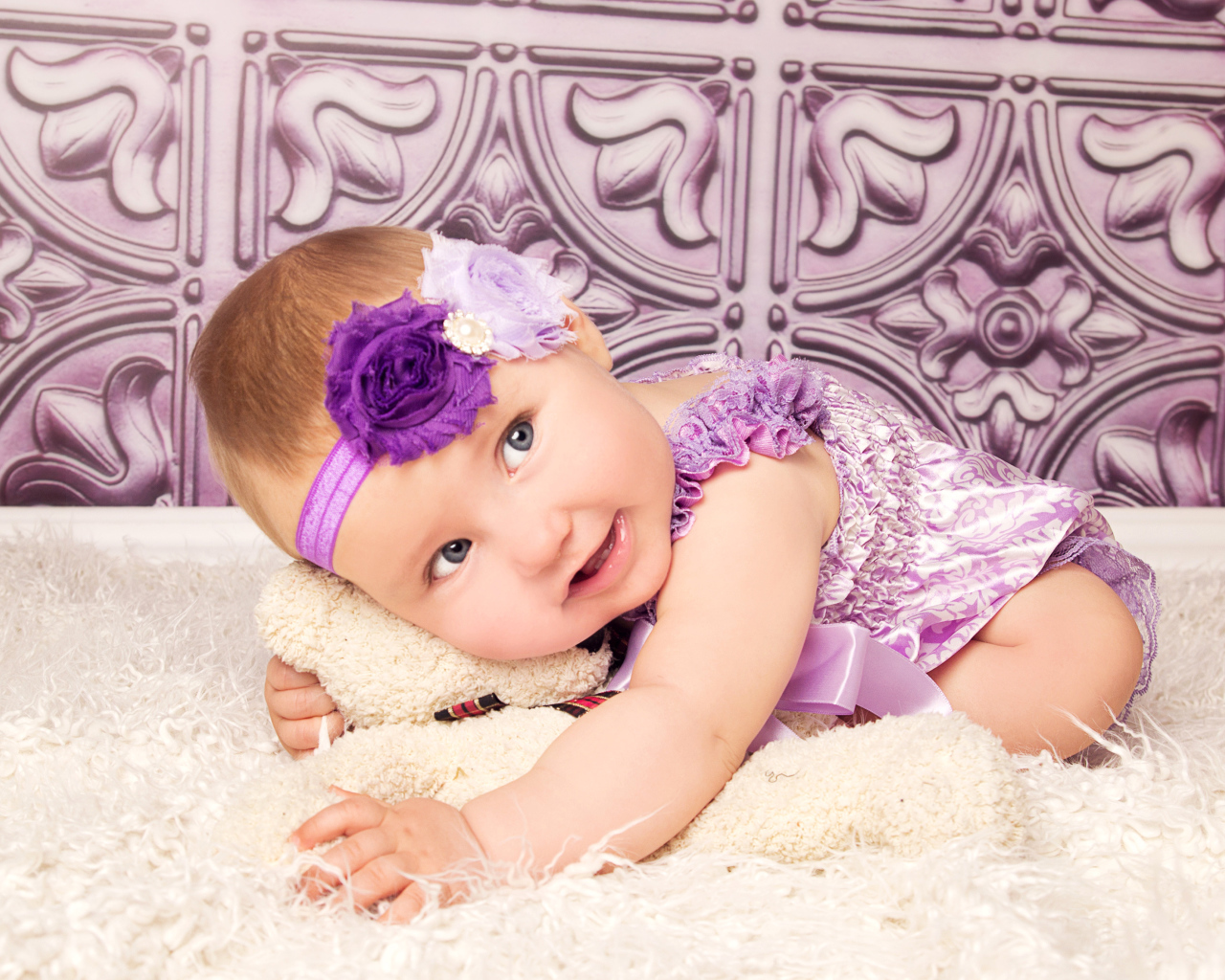 Красивая маленькая девочка в фиолетовом костюме с плюшевым мишкой