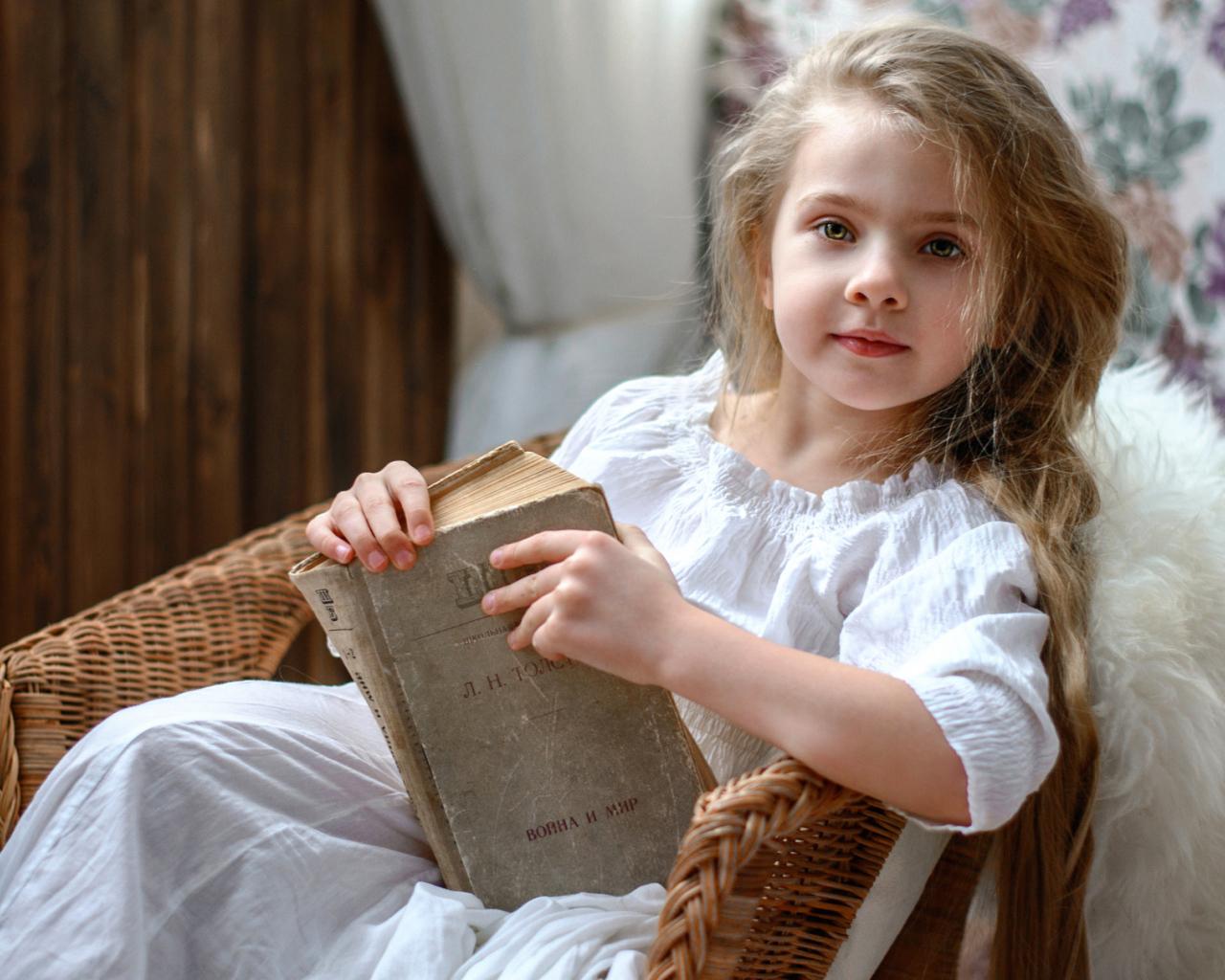 Красивая маленькая девочка в белом платье с книгой 