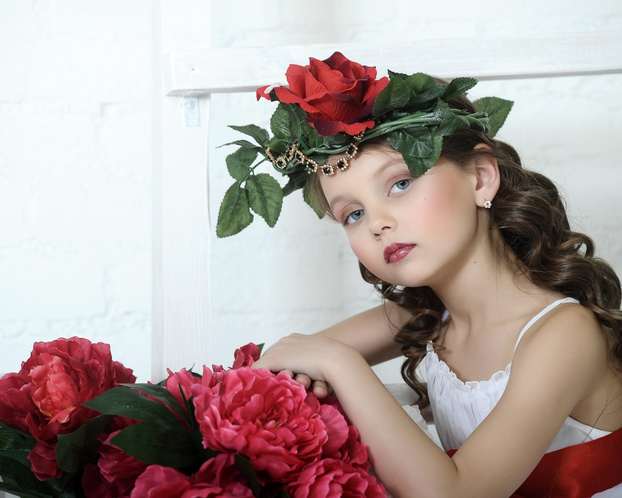 Красивая маленькая девочка с венком из роз на голове